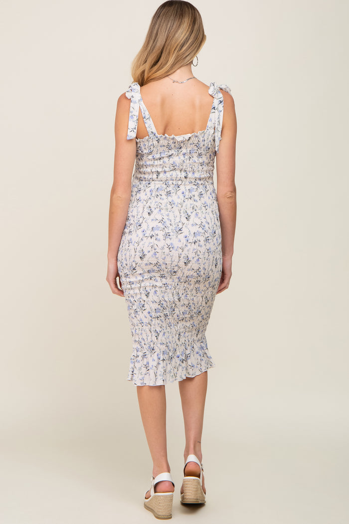 woman wearing a floral print maternity dress with ruffled hem and tie straps, showing a baby bump from the back