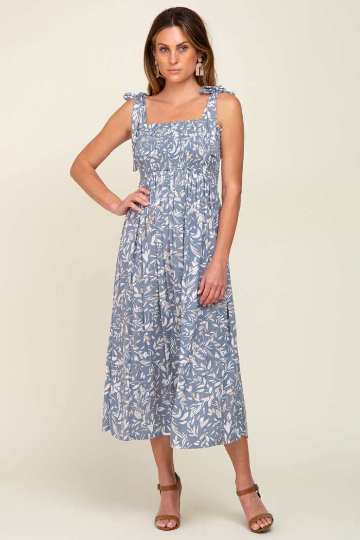woman wearing a blue floral smocked midi dress with tie straps and brown sandals