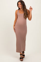 woman wearing a beige sleeveless maternity maxi dress with a fitted style and visible baby bump