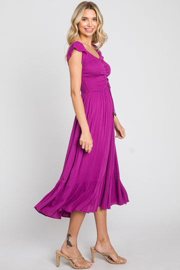 woman wearing a bright purple midi dress with ruffled sleeves and a flowing skirt, smiling and standing sideways