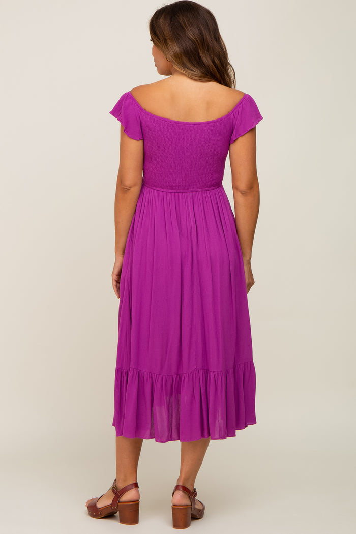 woman wearing a back view of a purple short sleeve maternity dress with a ruffled hemline