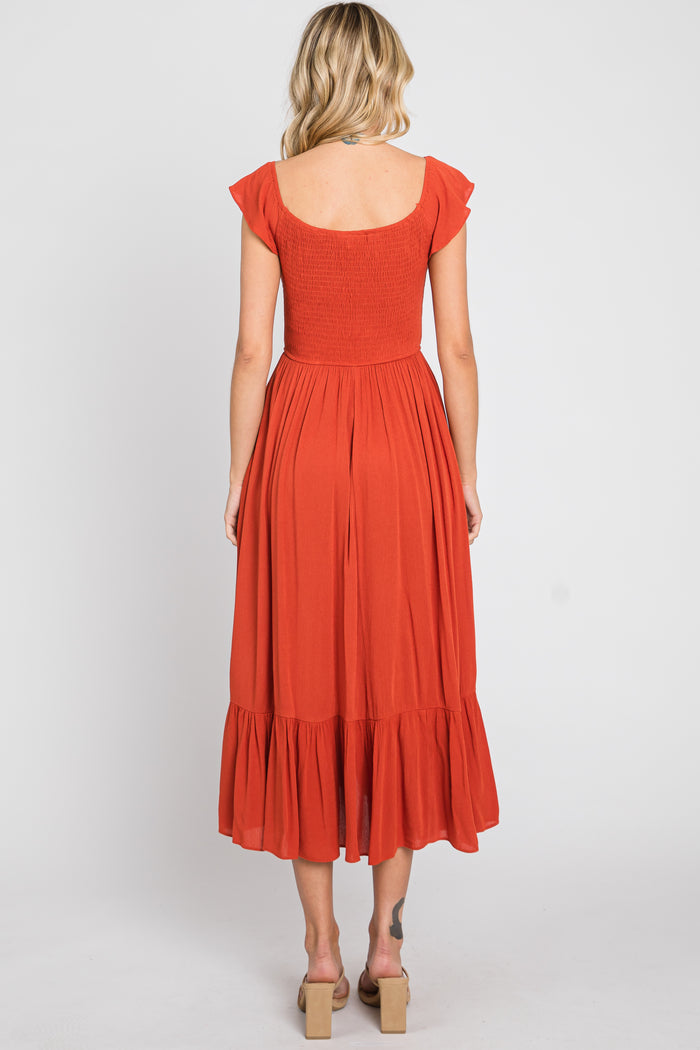 woman wearing an orange smocked back midi dress with flutter sleeves and a ruffled hem