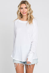 woman wearing a white long sleeve shirt with a loose fit and distressed hems, paired with light blue denim shorts