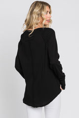 woman wearing a black long sleeve top with a unique back detail and white pants