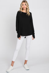 woman wearing a black long sleeve top with relaxed fit and white skinny jeans, paired with white sneakers