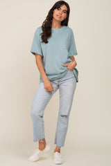 woman wearing a teal oversized t-shirt with a pocket and light wash ripped jeans, standing in casual pose