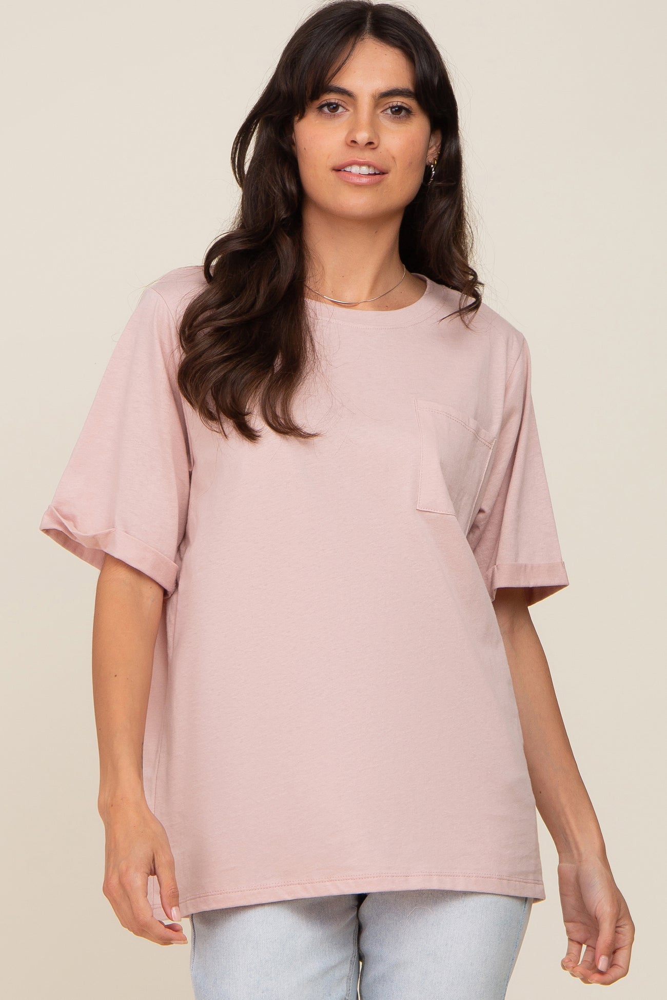 woman wearing a light pink oversized t-shirt with short sleeves and a front pocket.