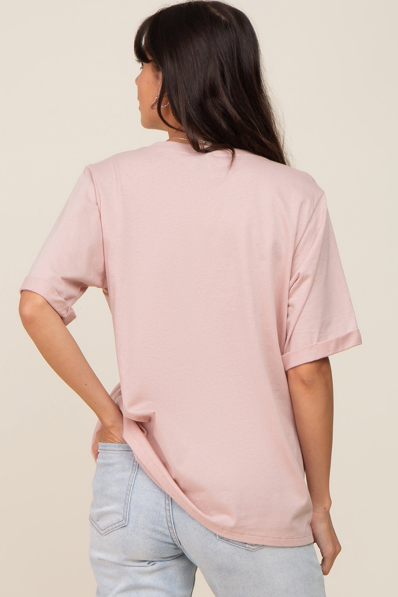 woman wearing a light pink oversized t-shirt with short sleeves and a relaxed fit, showing the back view