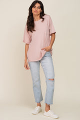 woman wearing a light pink oversized t-shirt with a pocket and distressed light blue jeans, standing casually