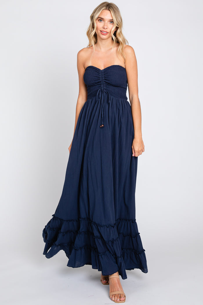 woman wearing a navy blue strapless maxi dress with a smocked bodice and ruffled hem
