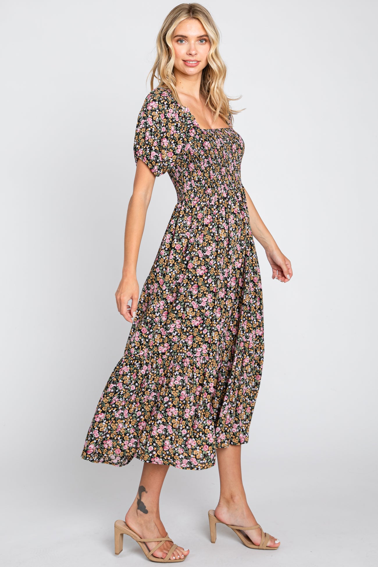 woman wearing a black floral midi dress with puff sleeves and a fitted bodice, posing sideways