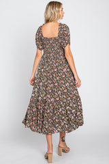 woman wearing a black floral midi dress with short puff sleeves and a square neckline, standing with her back to the camera