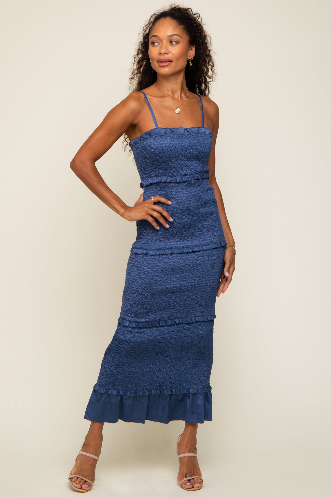woman wearing a navy blue smocked maxi dress with ruffled details and thin straps