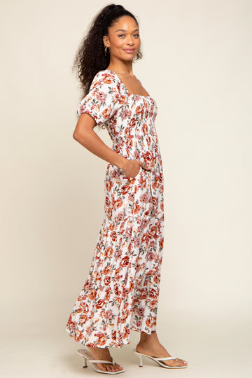 woman wearing a white floral maxi dress with puff sleeves and pockets, standing in a relaxed pose