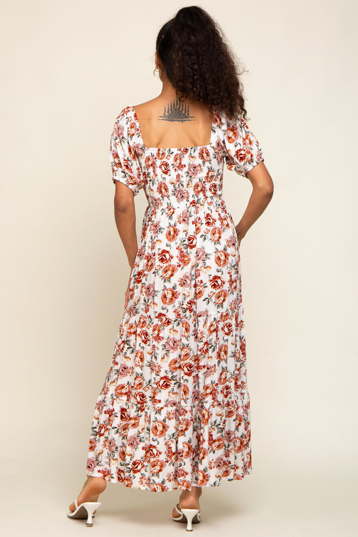 woman wearing a white floral maxi dress with puff sleeves and a square back, showing off a tattoo on her back