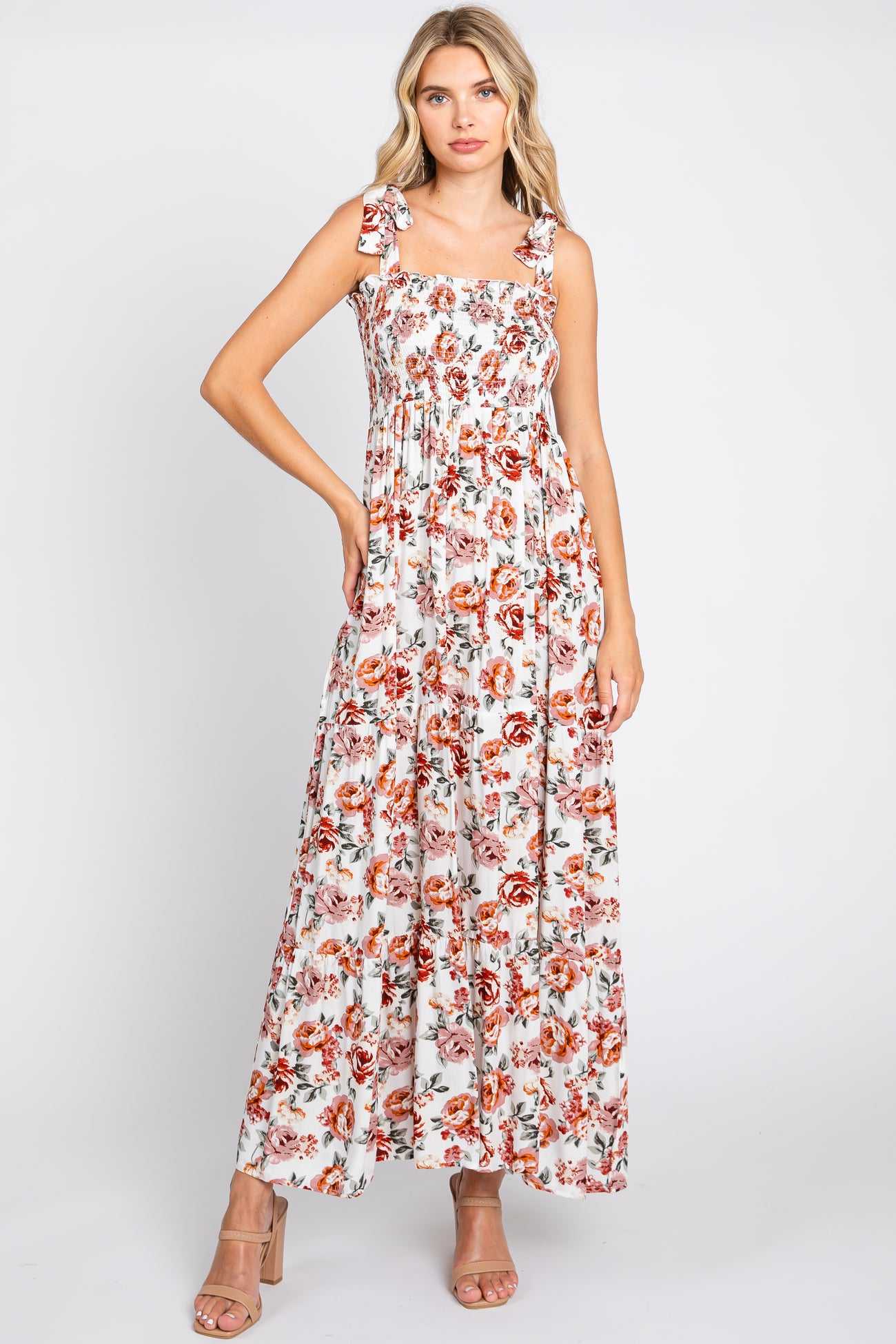 woman wearing a floral maxi dress with square neckline and tie straps, styled with nude high-heeled sandals