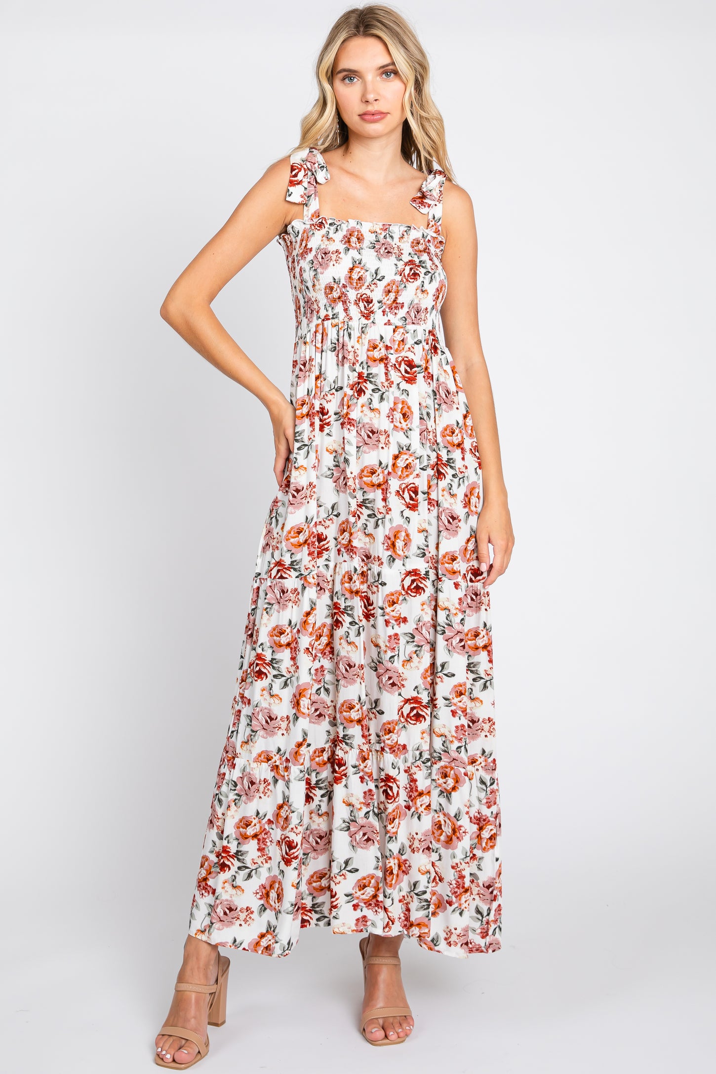 woman wearing a floral maxi dress with square neckline and tie straps, styled with nude high-heeled sandals