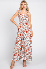 woman wearing a floral maxi dress with square neckline and tie straps, styled with nude high-heeled sandals
