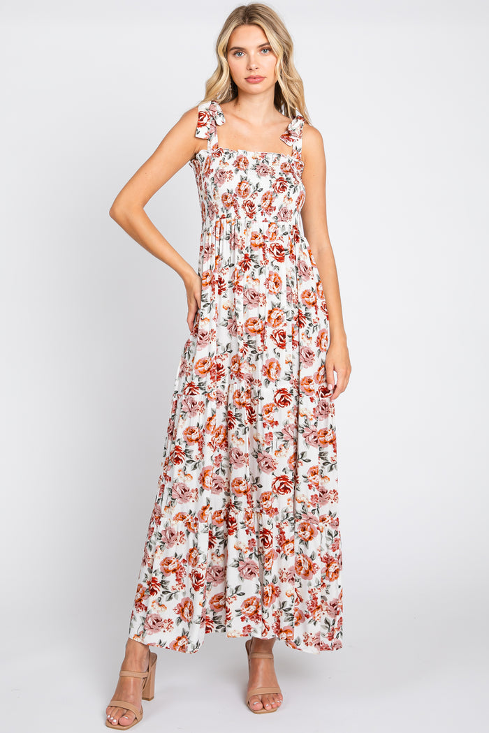 woman wearing a floral maxi dress with square neckline and tie straps, styled with nude high-heeled sandals