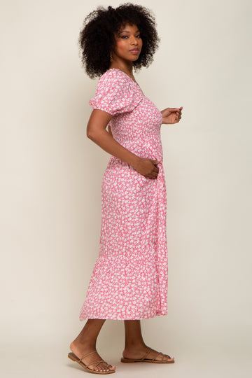 Woman with curly hair wearing a pink and white floral puff sleeve midi dress and tan sandals
