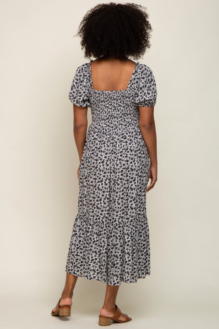 woman wearing a white and black floral print midi dress with puff sleeves and a ruffled hem