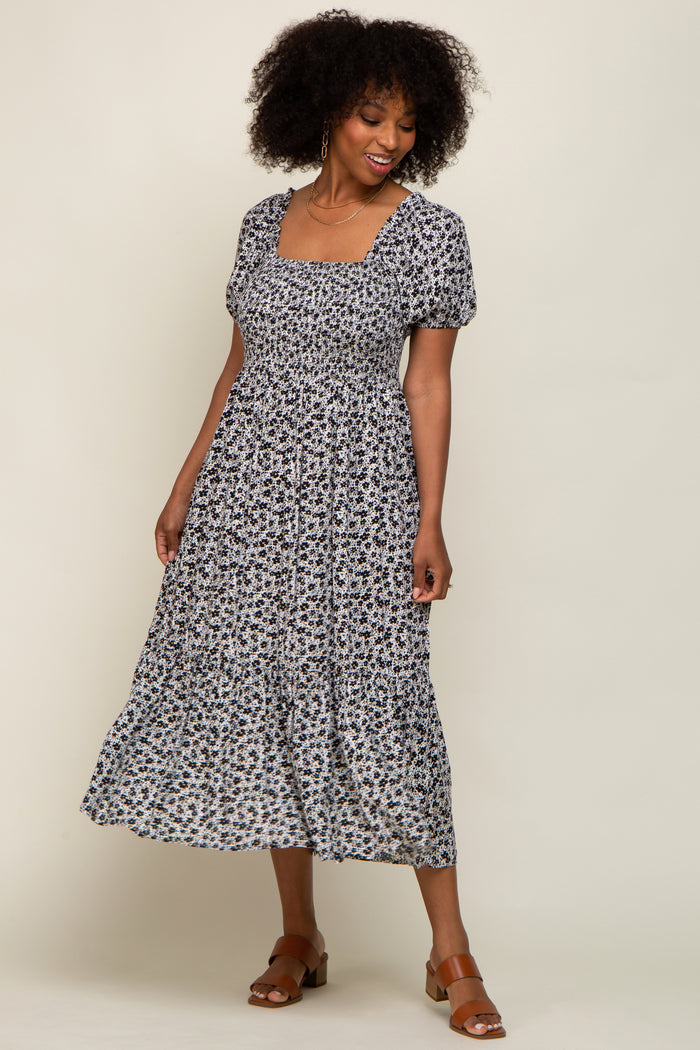woman wearing a black and white floral print midi dress with puff sleeves and a square neckline