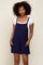 woman wearing a navy blue romper with pockets over a white fitted t-shirt and styled with curly hair