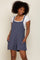 woman wearing a navy blue sleeveless romper with a square neckline and front pockets, smiling against a neutral background