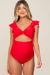 woman wearing a red maternity swimsuit with ruffle sleeves and a cutout design, showcasing her baby bump