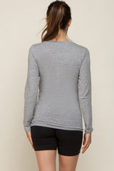 woman wearing a gray long sleeve maternity top with a loose fit, viewed from the back, paired with black shorts