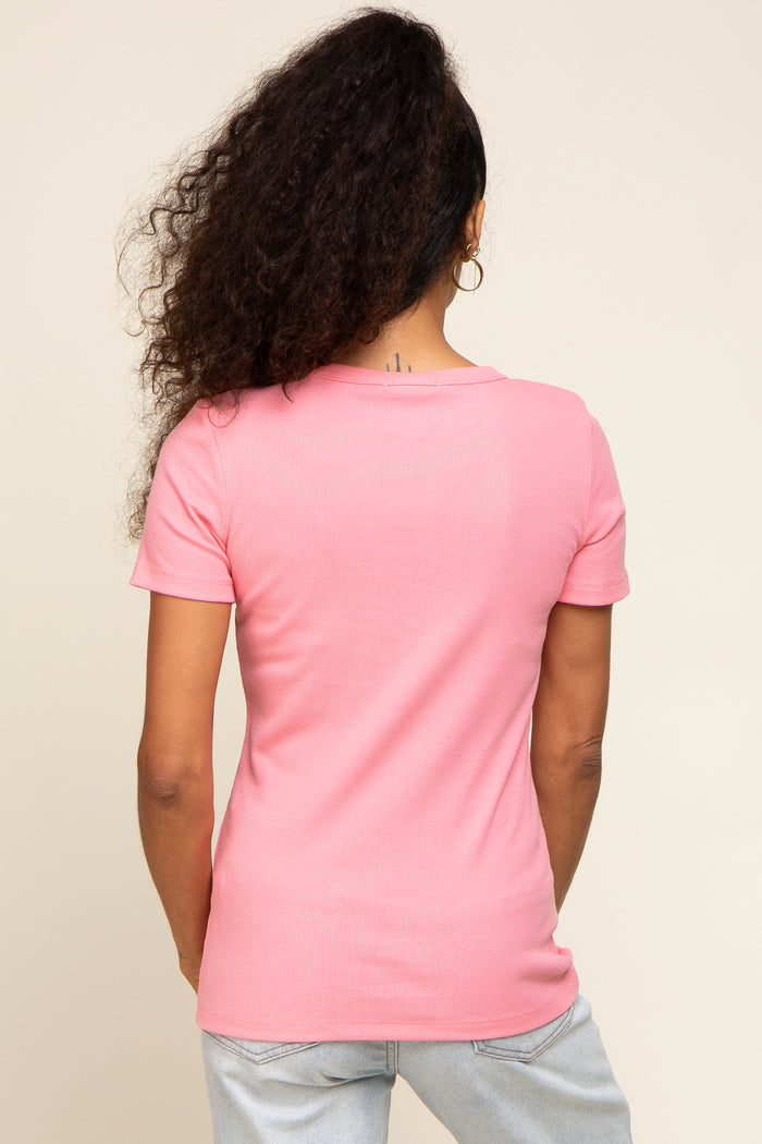 woman wearing a light pink short sleeve fitted top, seen from the back, with curly hair and hoop earrings