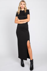 woman wearing a black short sleeve maxi dress with a side slit and paired with black ankle boots