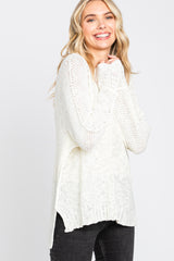 woman wearing a cream knit sweater with long sleeves and side slits, smiling with hands in front of her face