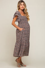 woman wearing a brown floral maternity dress with ruffled sleeves and pockets, showing her baby bump