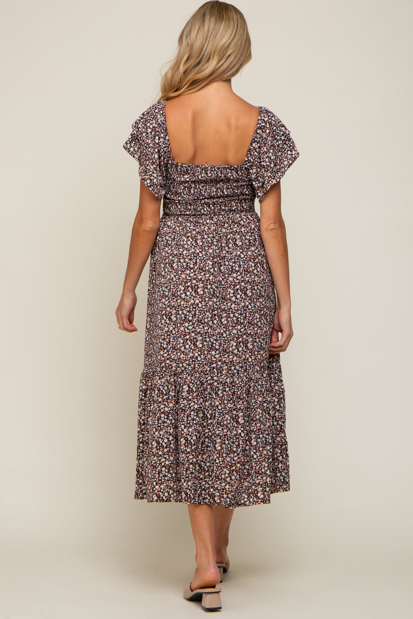 Back view of a woman wearing a floral smocked midi dress with flutter sleeves and a square neckline