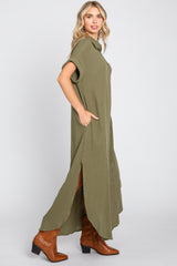 woman wearing an olive green short sleeve button-up maxi dress with side slits and brown cowboy boots