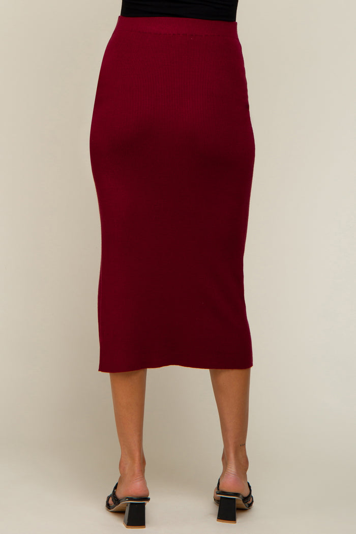 Back view of a woman wearing a burgundy ribbed midi skirt and black block heel sandals