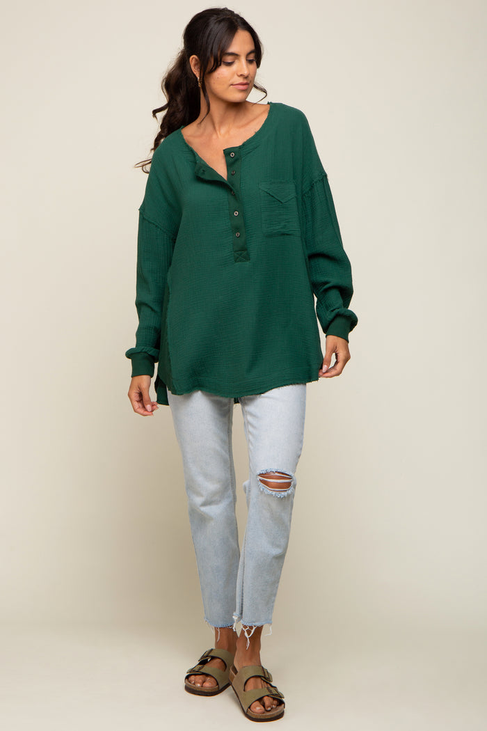 woman wearing a green waffle knit oversized henley shirt with buttons and a pocket, paired with light blue ripped jeans and sandals
