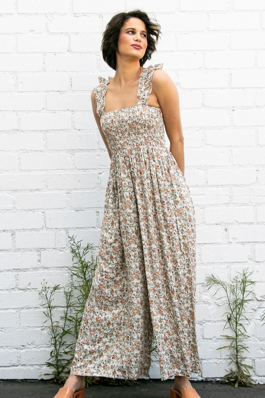 woman wearing a sleeveless floral maxi dress with ruffled straps and a fitted bodice
