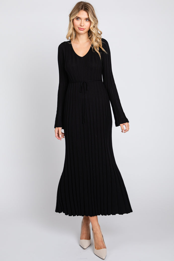 woman wearing a black ribbed knit maxi dress with a v-neck and long sleeves, featuring a tied waist detail