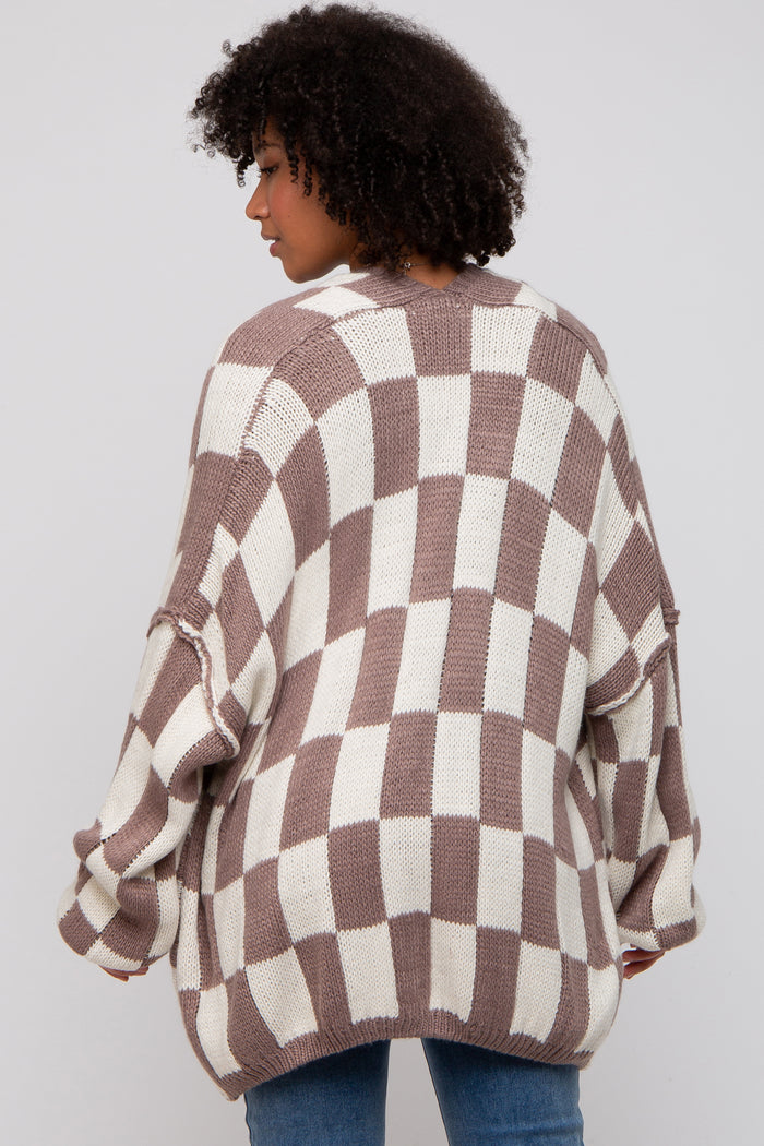 woman wearing a brown and cream checkered oversized sweater, viewed from the back, paired with blue jeans