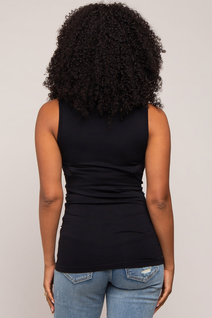 woman wearing a black sleeveless fitted top, viewed from the back, paired with light blue skinny jeans