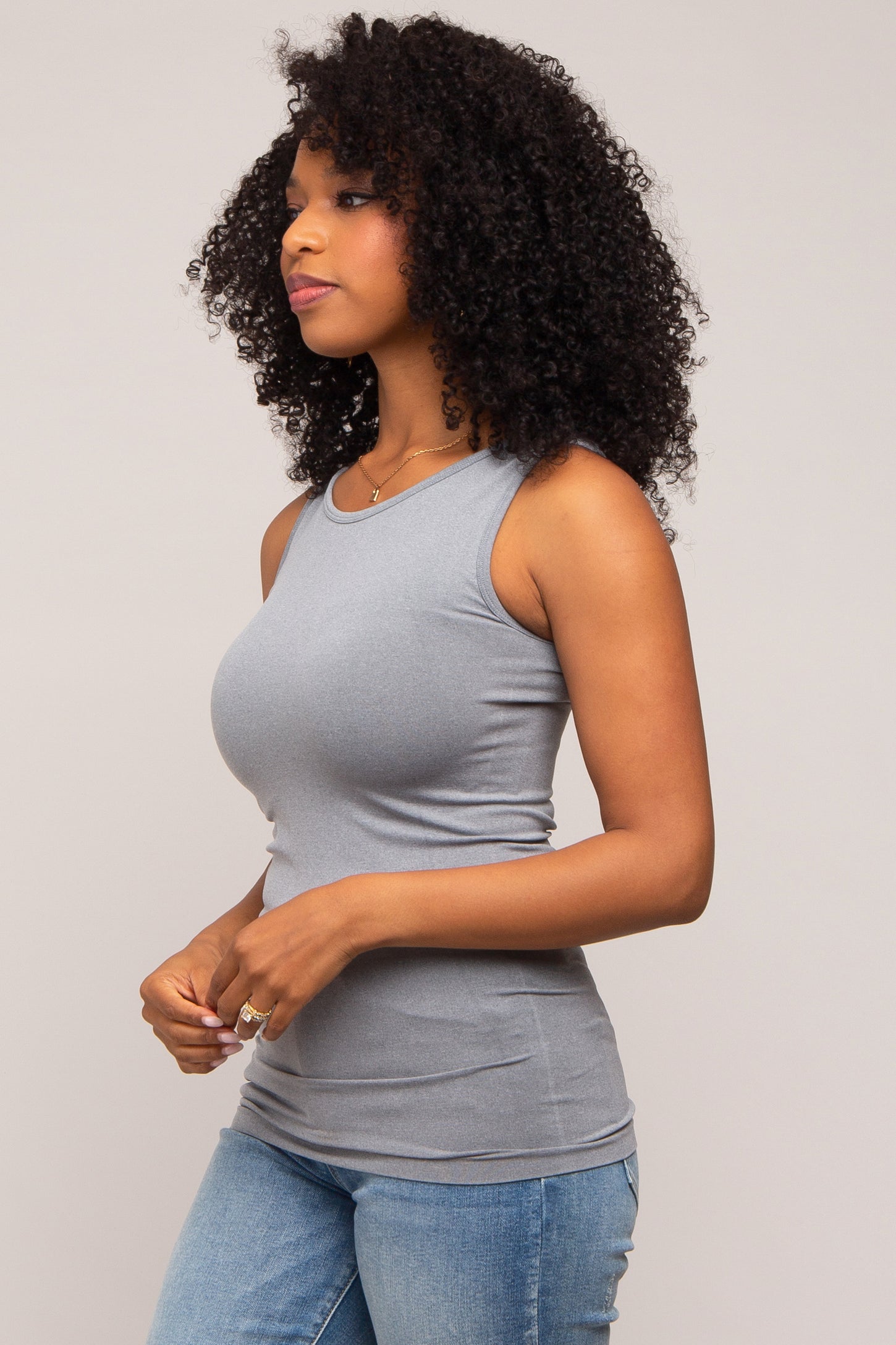 woman wearing a gray sleeveless fitted top paired with blue jeans