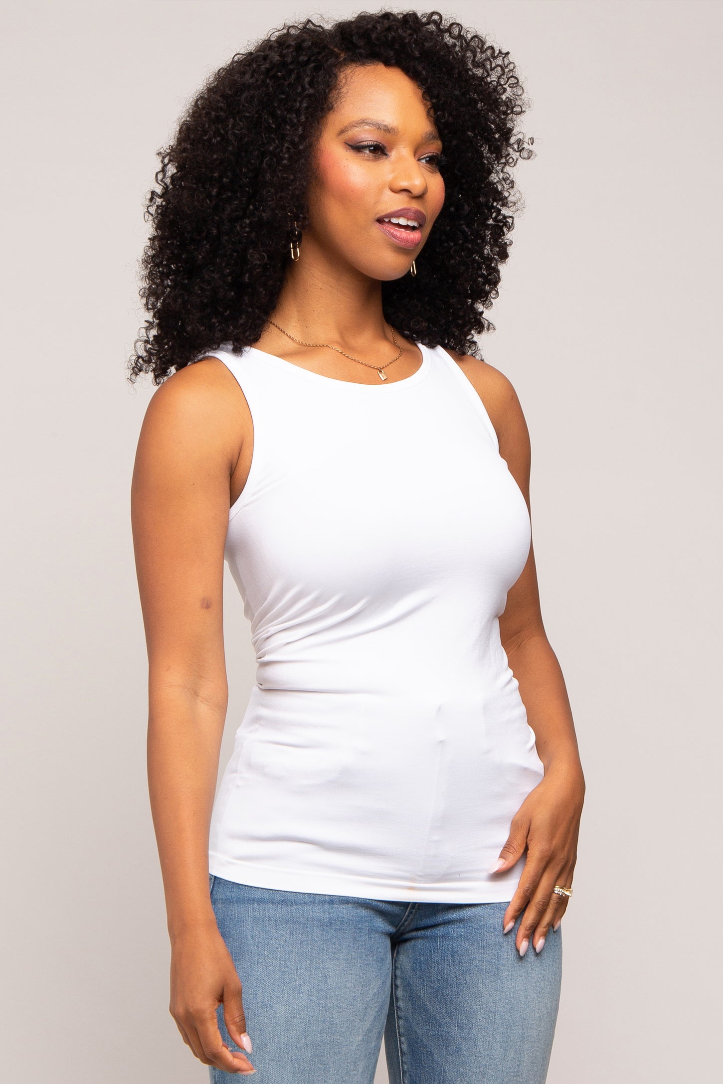 woman wearing a white sleeveless tank top with a fitted style and blue jeans