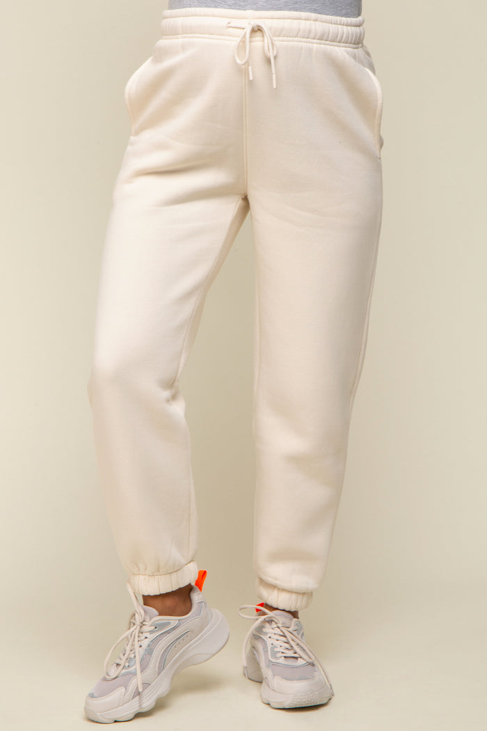 woman wearing cream maternity jogger pants with pockets and elastic cuffs, paired with light sneakers