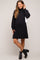 woman wearing a black maternity sweater dress with a turtleneck and long sleeves, showing her baby bump