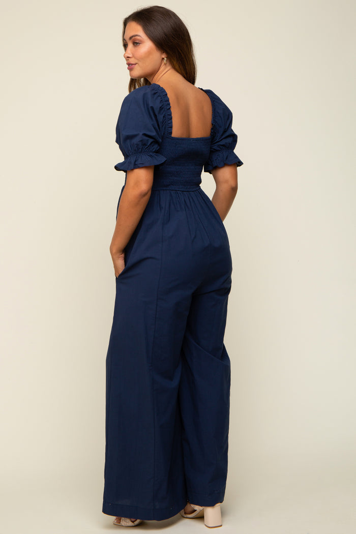 woman wearing a navy blue maternity jumpsuit with puff sleeves and a smocked back