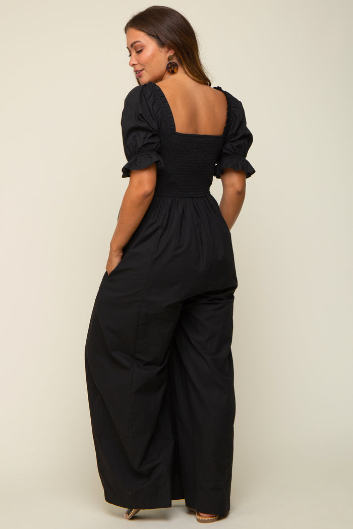 woman wearing a black maternity jumpsuit with puff sleeves and a smocked back, featuring a wide-leg silhouette
