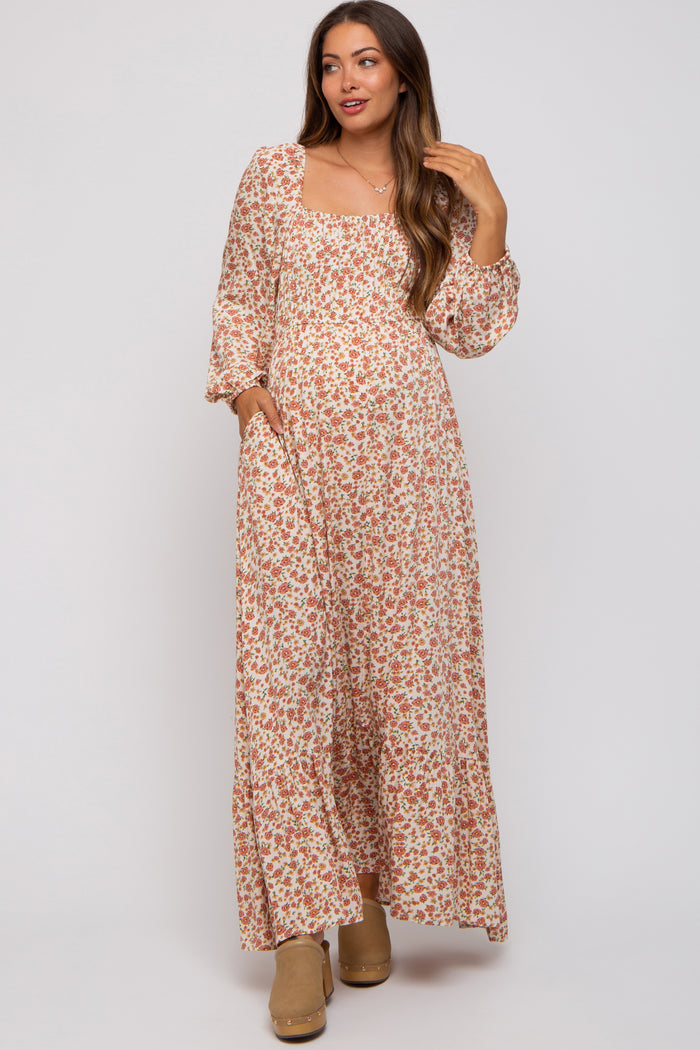 woman wearing a floral maxi dress with long sleeves and pockets, showcasing her baby bump in this maternity wear