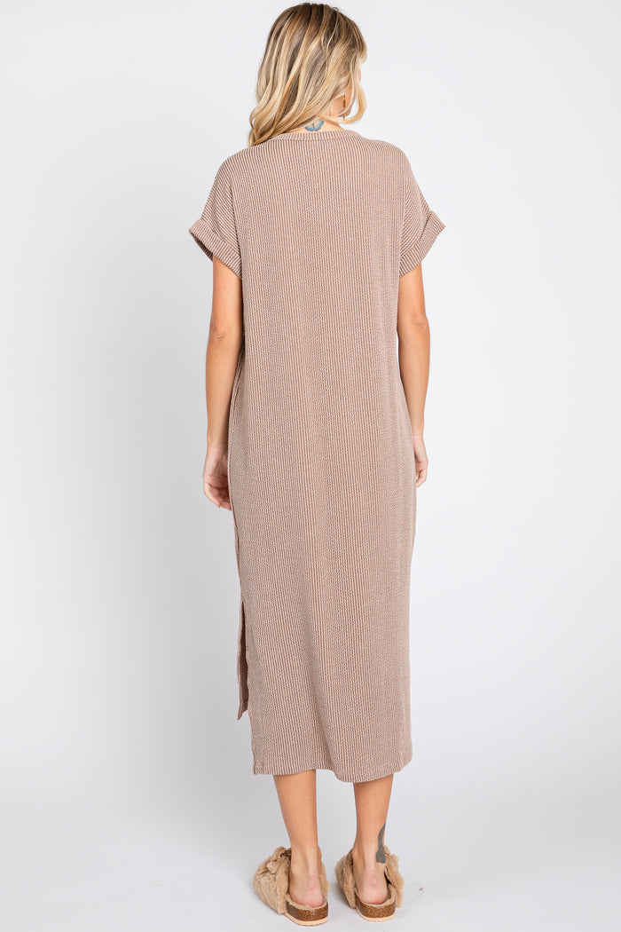 woman wearing a brown striped maxi dress with short sleeves and side slits, standing with her back to the camera